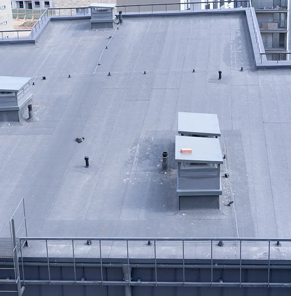 Large flat roof with a dark membrane, vent pipes, rooftop units and a metal railing